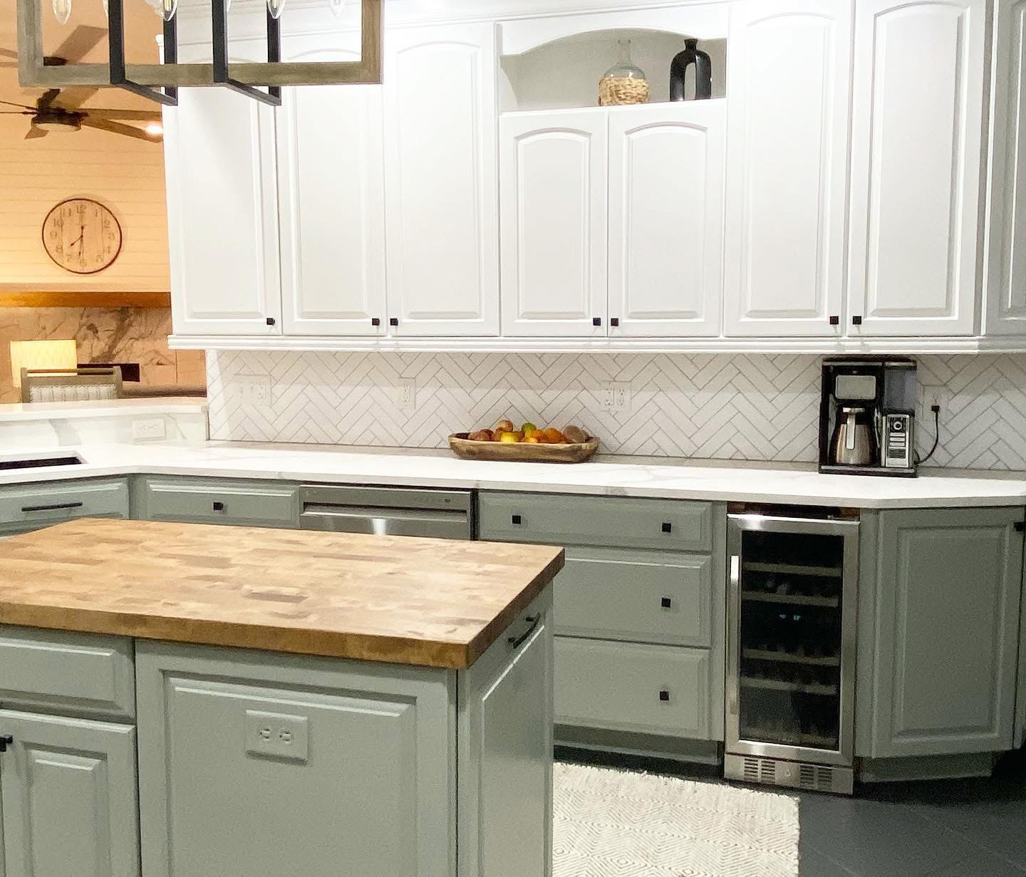 Two-tone kitchen with sage green lower cabinets and butcher block island