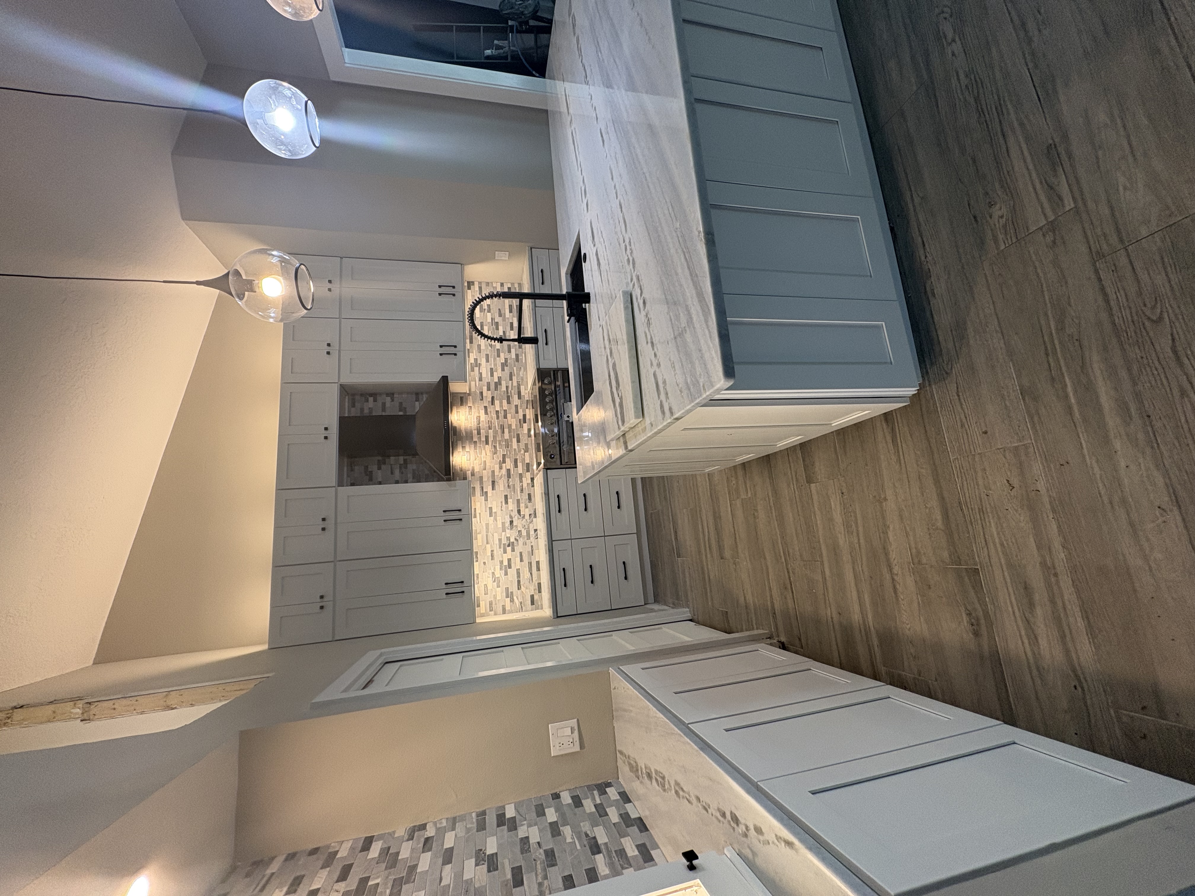 Kitchen remodel with white cabinetry, mosaic backsplash, and island with seating