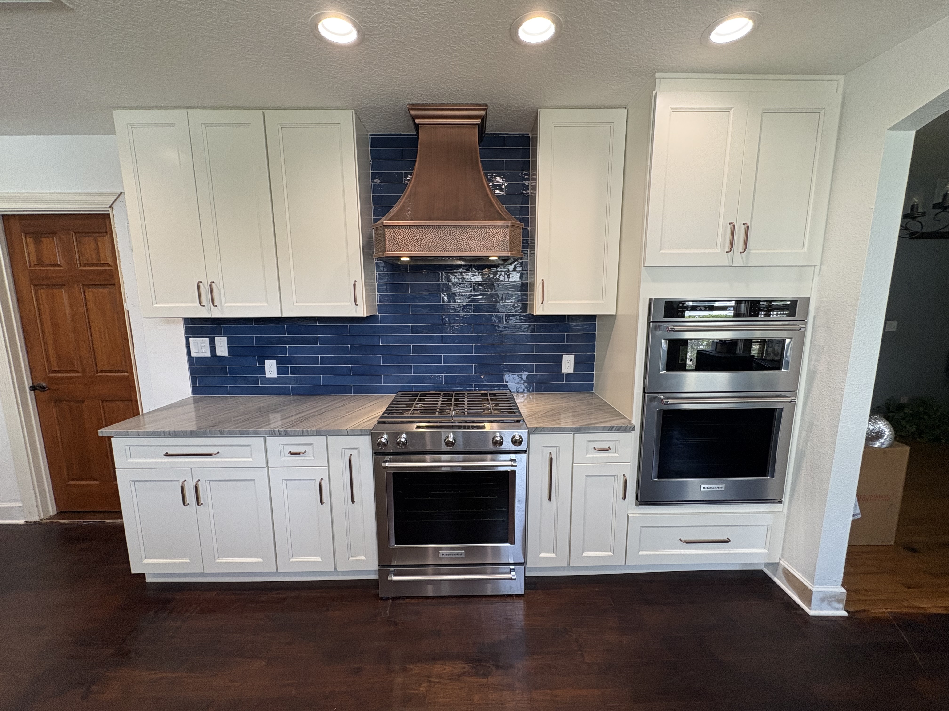 Kitchen with blue subway tile backsplash and copper range hood