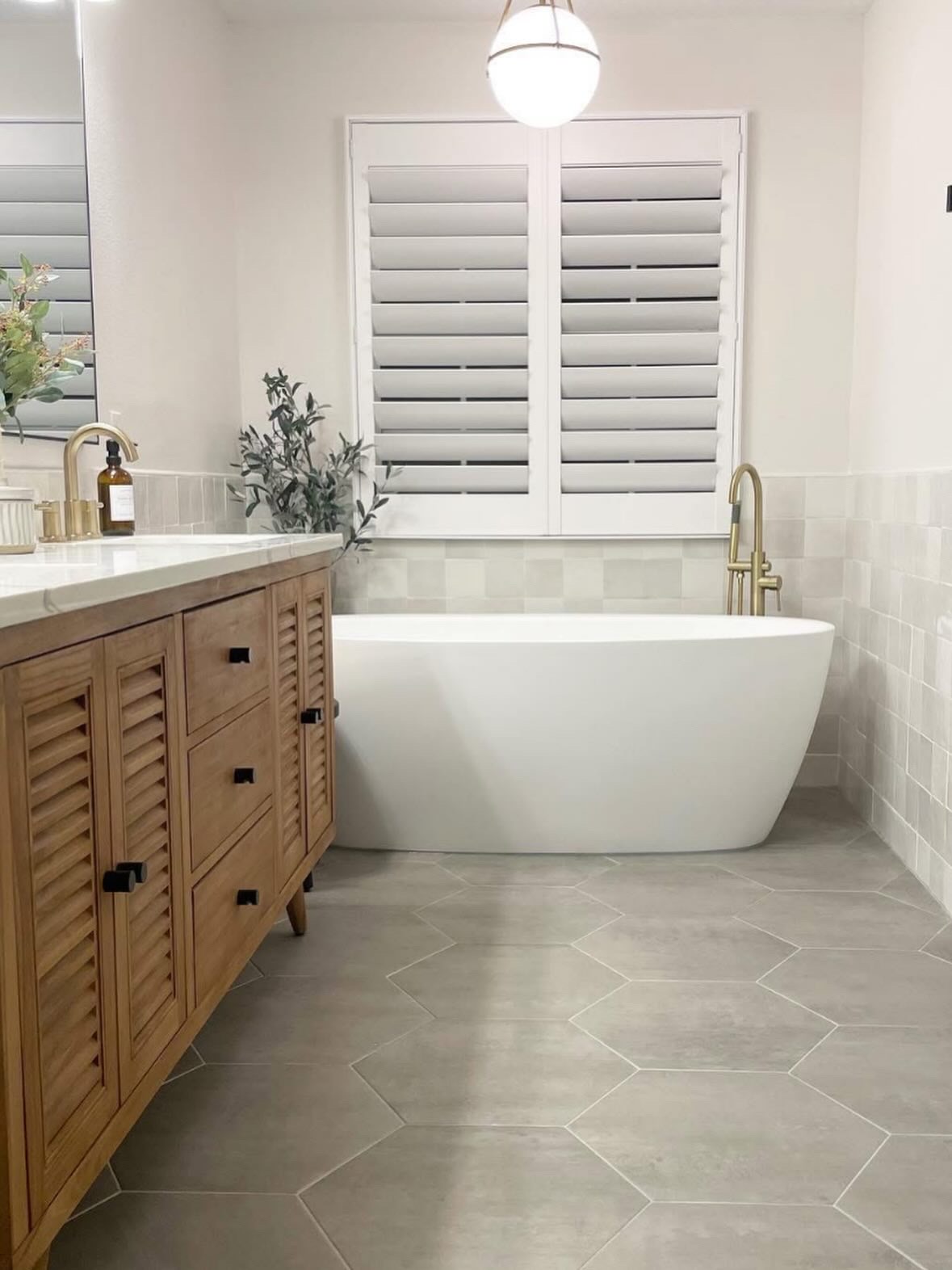 Bathroom remodel with freestanding soaking tub, hexagonal floor tile, and wood vanity with brass fixtures