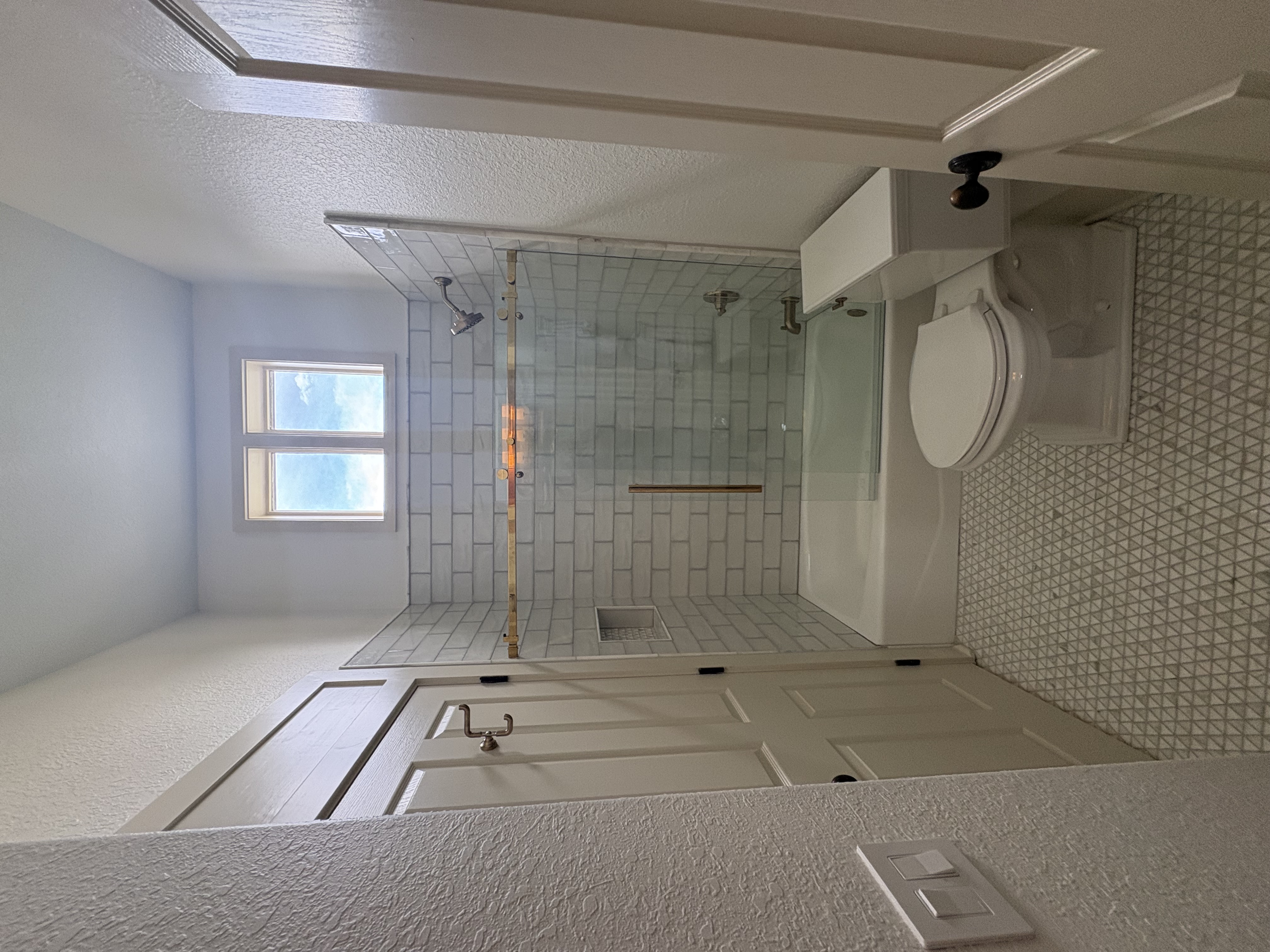 Full bathroom remodel with walk-in tile shower, glass enclosure, and white vanity