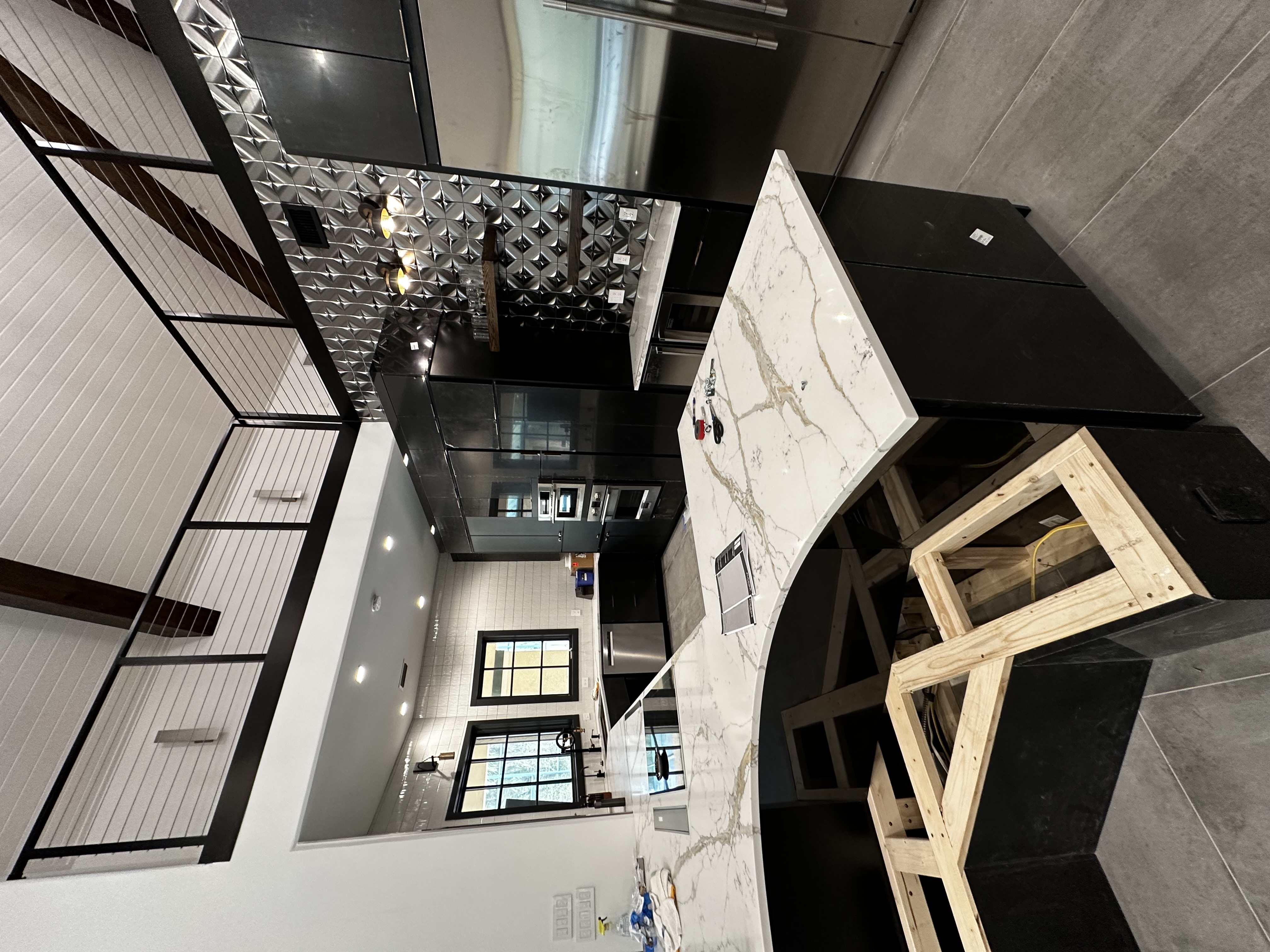 Bold black and marble modern kitchen with geometric ceiling tile and industrial windows