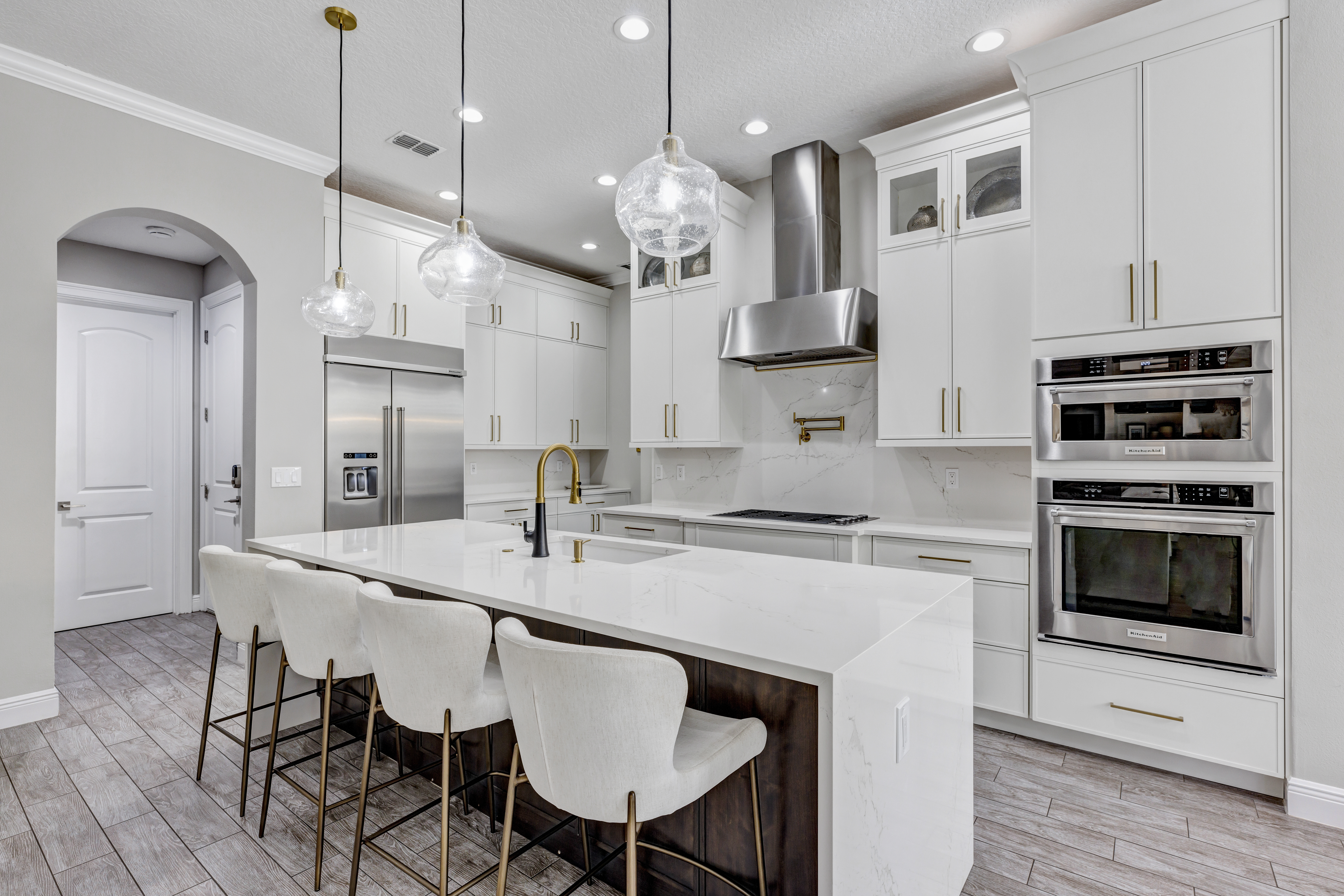 Viking Remodeling Solutions - luxury white kitchen with waterfall island and gold fixtures